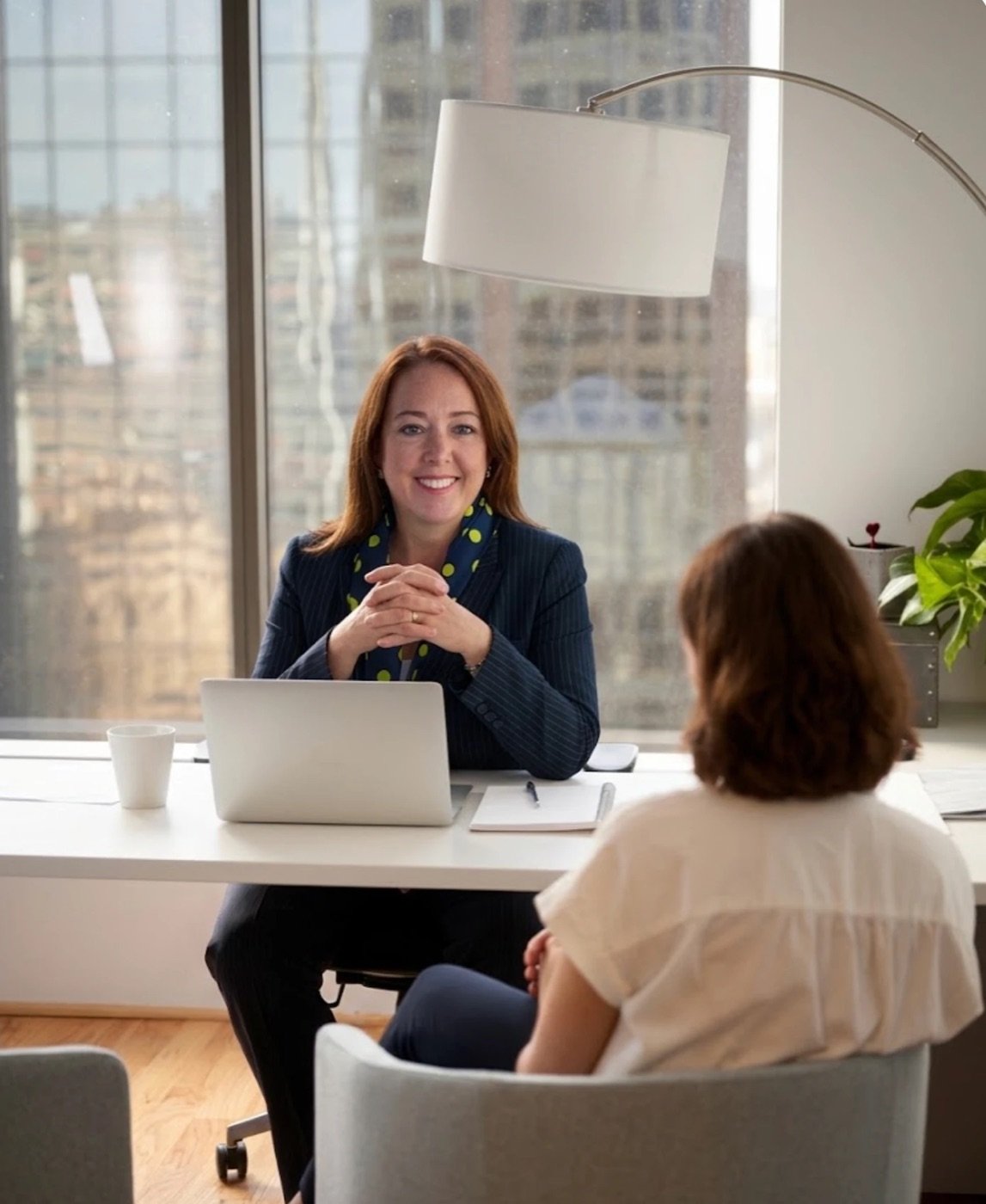 Janice Pierce smiling across her desk during a meeting with a client